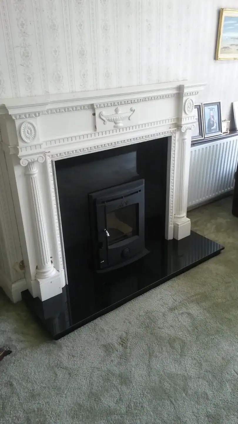 Elegant white fireplace with black insert and decorative mantelpiece.